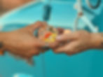 Close-up of two hands exchanging a tin of The Meat Bar Beef Chew in front of a vintage turquoise truck.