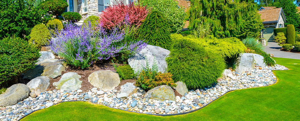 Landscaped area featuring beautiful shrubs, bushes, and decorative rocks arranged attractively.