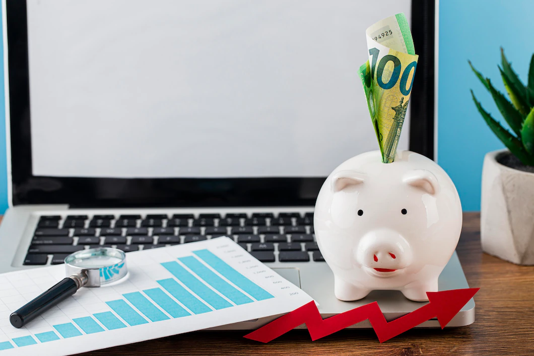 high-angle-office-items-with-piggy-bank-laptop_23-2148780578.webp