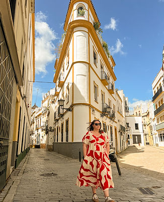 A girl in a red dress on a sunny Seville street