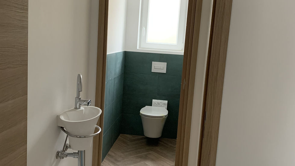 Lave mains suspendu et wc avec carrelage vert et sol chevron