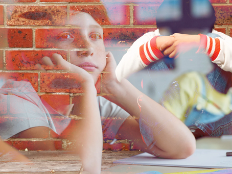 Young person sits against a brick wall, looking thoughtful. Another is seen with arms around knees. Warm tones and layered images.