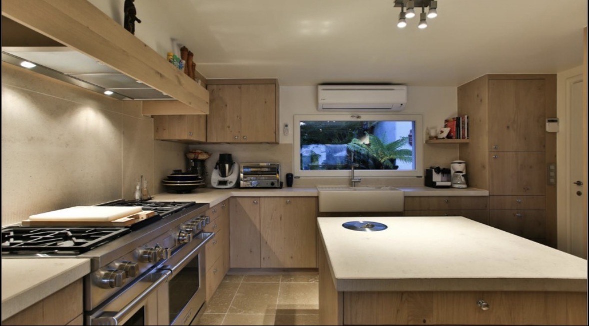 Fully equipped modern villa kitchen with wooden cabinetry, a large island, and premium appliances.