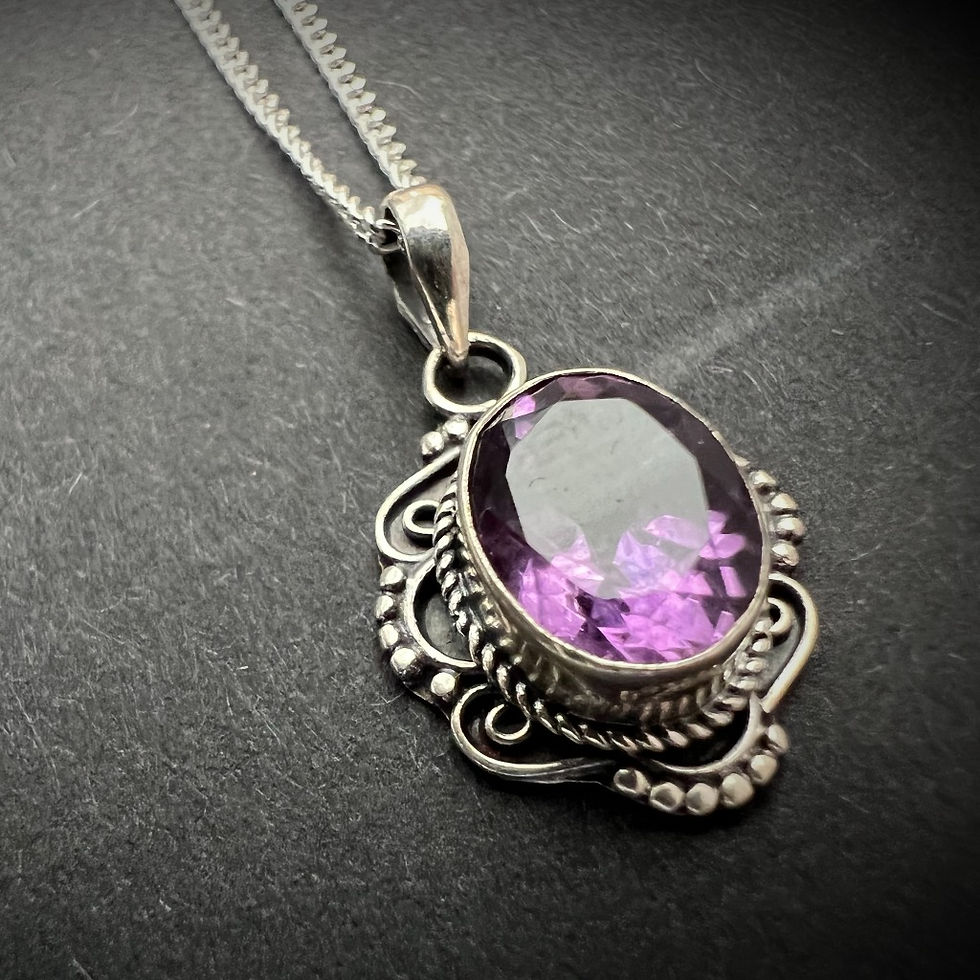 Thumbnail: A handcrafted pendant necklace featuring a purple amethyst gemstone set in silver plated brass floral detailing, and chain.