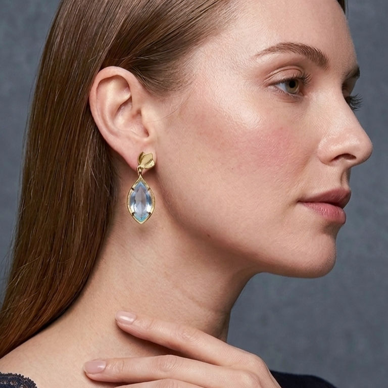 Woman wearing Tulip Drop Earrings featuring tulip-shaped sky blue Quartz stones set in 22 carat gold