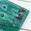 Thumbnail: Fused glass coaster featuring two copper dolphin motifs in a corner in a sea of bubbles.
