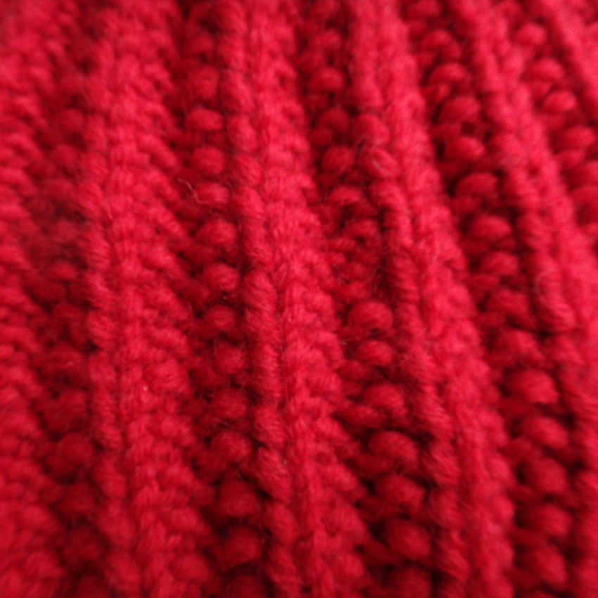 Thumbnail: Close-up of Hand-knitted Chunky Red Beanie features eatures dramatic ribbed texture.