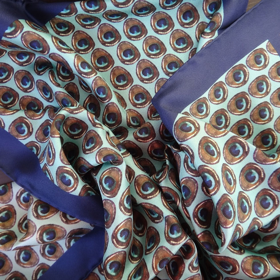 Peacock feather print scarf on a turquoise base, hand-rolled edges and enhanced by a thick dark blue border.