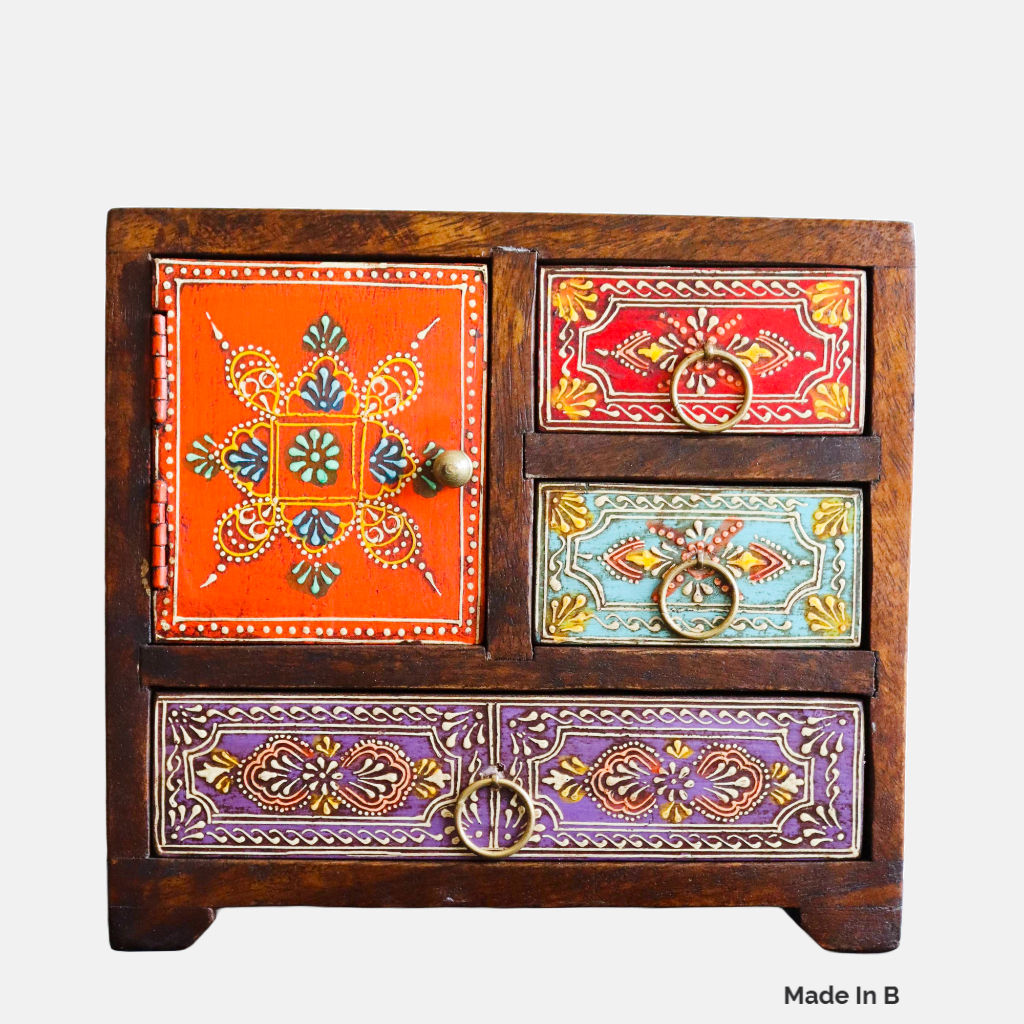 Exquisitely hand-painted, this hand painted mango wood chest features three drawers and a petite door