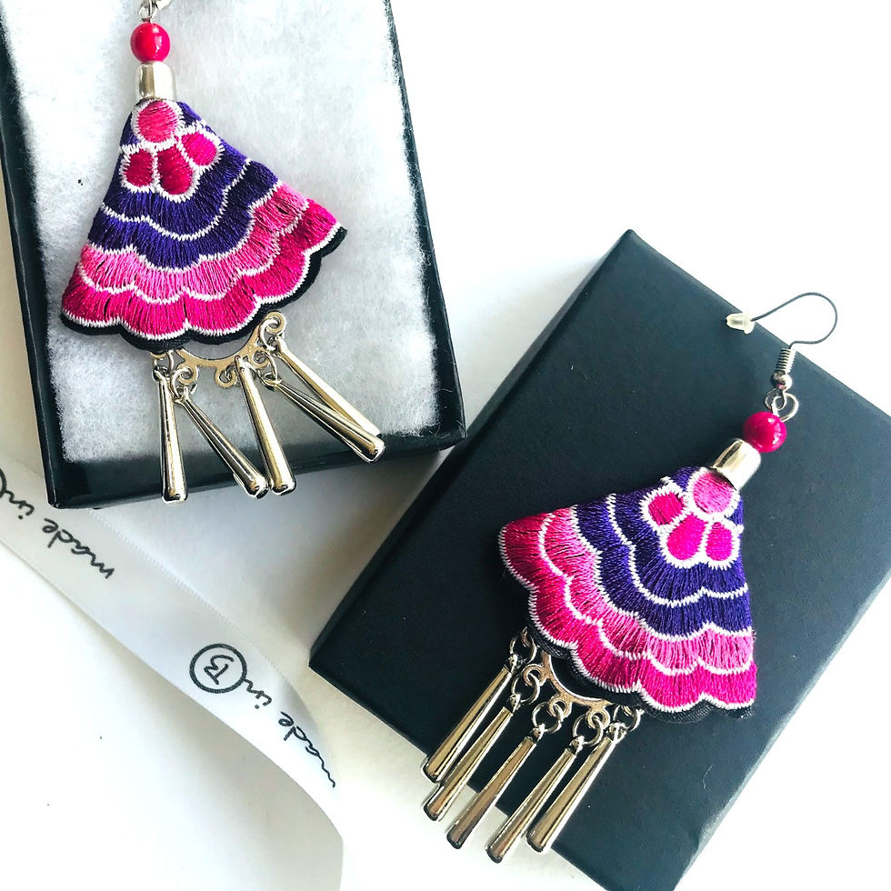 Thumbnail: Embroidered earrings in wavy pink and purple embroidery shaped like a fan and suspended from a hook in a black packaging box.