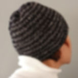 Woman wearing hand-knitted wool beanie, crafted from black and silver textured wool for a subtle shimmer.