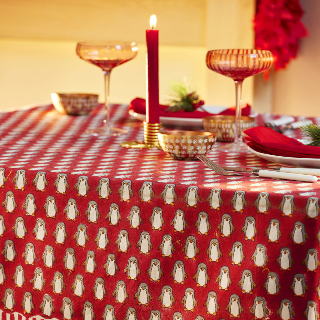 Penguin Block Print Christmas Tablecloth features waddling penguins in repeat pattern hand block printed against a red base.