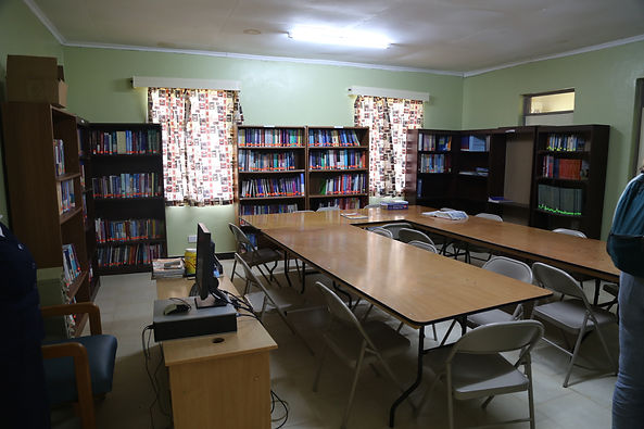Book room with brown bookshelves and a U-shaped wooden desk. Bookshelves are full of medical textbooks and reference materials. Computer in one corner