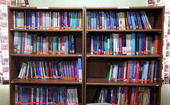 Image of colorful medical textbooks on a brown wooden bookshelf.