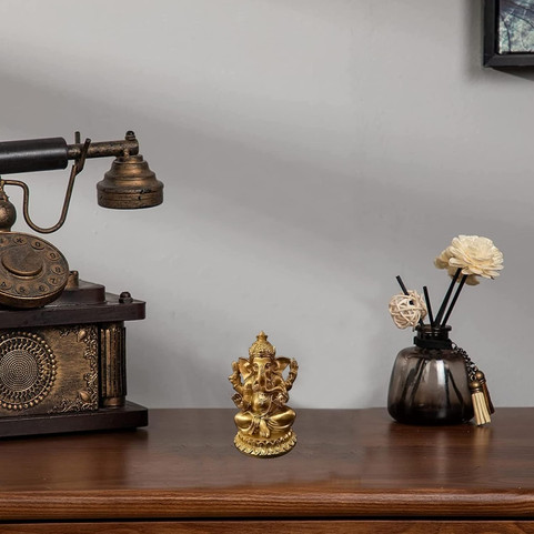 Gouden Ganesha-beeldje op een bruine tafel, antieke telefoon, bloemen. Zen en So.