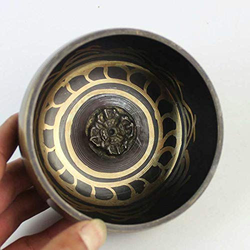 Hand holding a bronze singing bowl with detailed golden patterns Zen and So