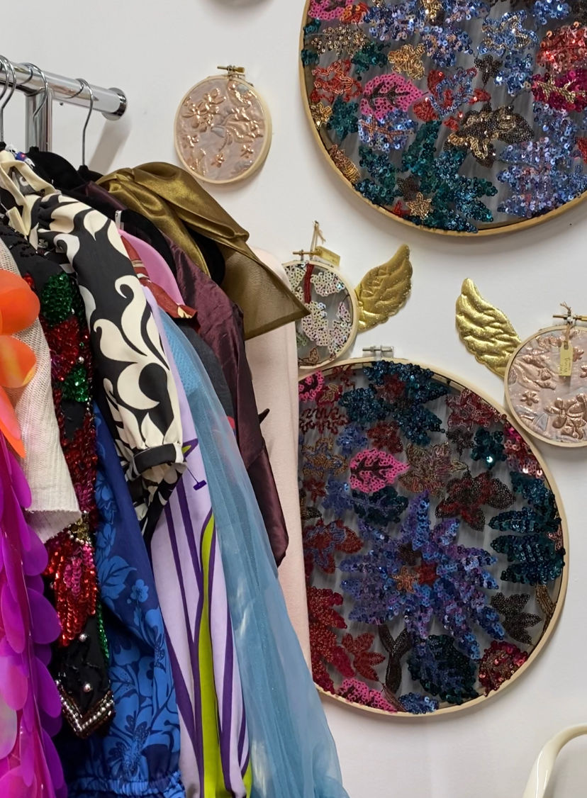 Rack of vintage clothes and embroidery hoops.