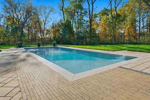 Fiberglass pool with modern paver layout and limestone coping in Pittsburgh
