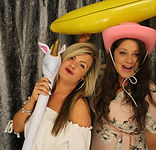 2 women enjoying a photo booth in southampton, wearing cowboy hats and holding inflatable props