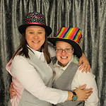Married couple hugging in a photo booth, wearing novelty hats
