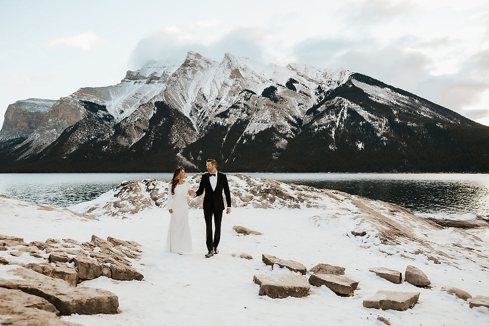 A couple celebrates their winter elopement against the stunning backdrop of snow-capped mountains and serene waters at Lake Minnewanka.