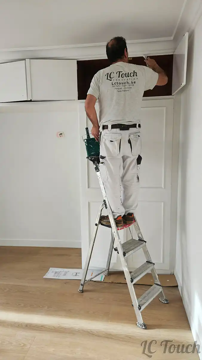 Peintre de l’équipe LC Touch appliquant les finitions sur un meuble rénové dans un appartement en cours de réfection