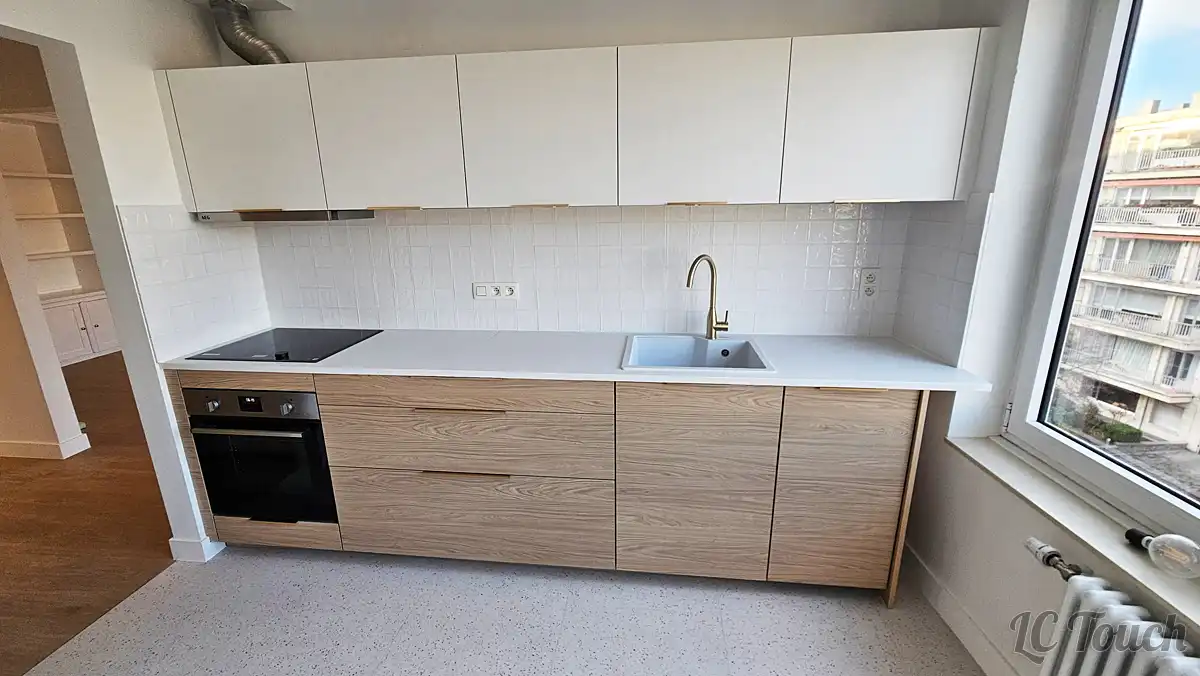 Cuisine rénovée à Bruxelles avec façade bois, plan de travail blanc, crédence carrelée et électroménager intégré