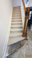 Escalier rénové avec revêtement antidérapant beige et rampe en bois restaurée, offrant une touche élégante et sécuritaire.