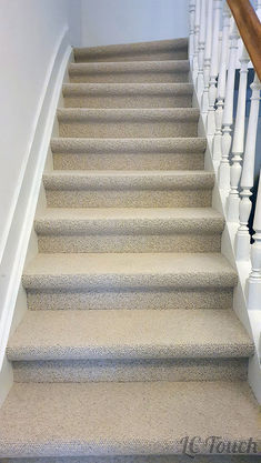 Escalier rénové avec revêtement moquette beige, rambarde blanche et bois pour un style classique et élégant