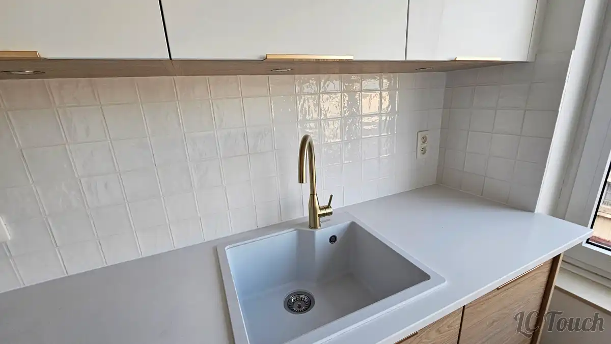 Évier blanc avec robinet en laiton et crédence carrelée dans une cuisine rénovée à Bruxelles