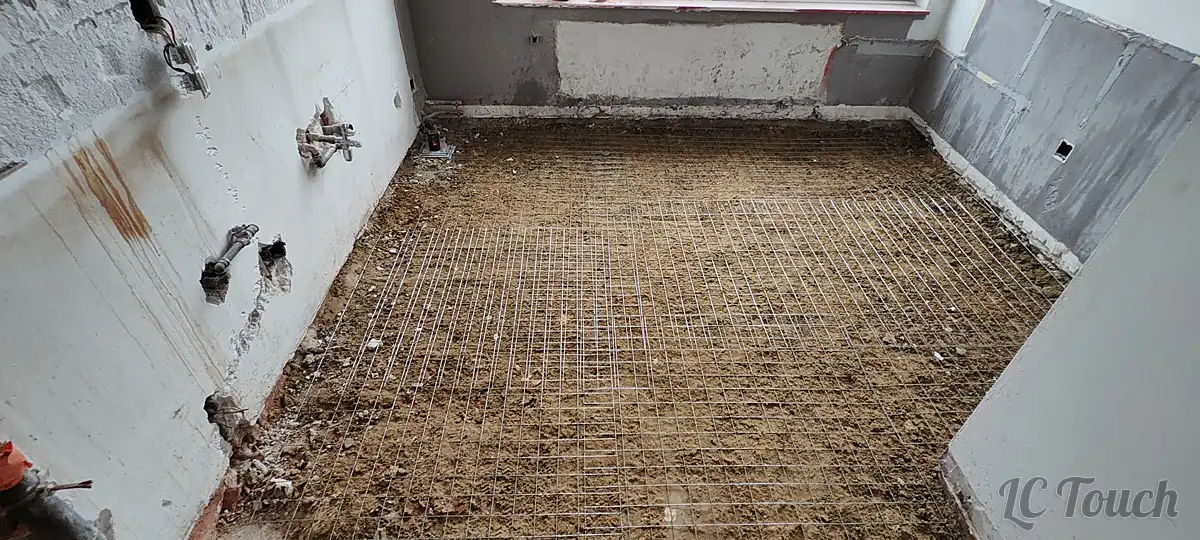 Préparation du sol après démolition avec réseau de treillis métallique installé avant la nouvelle chape dans la future cuisine.