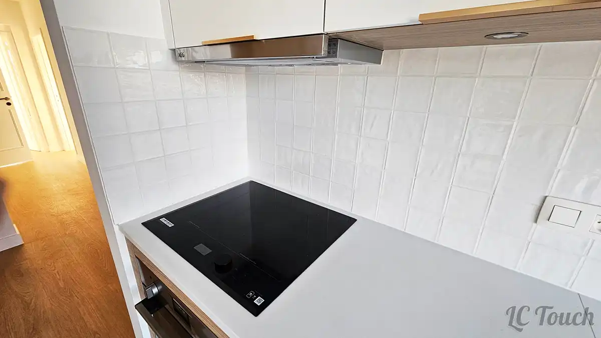 Plaque de cuisson encastrée et crédence en carrelage blanc dans une cuisine rénovée