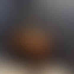 Table ancienne avec lampe dorée, devant un mur texturé en papier peint géométrique sombre.