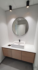 Lavabo moderne avec miroir rond et meuble en bois, style épuré dans une salle de bains rénovée.