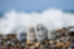 Group of stones with drawn faces in the sand. Father, mother, daughter and son. Concept of