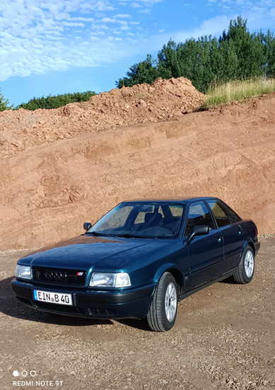 Dunkelblauer Audi 80 vor Sandhügel