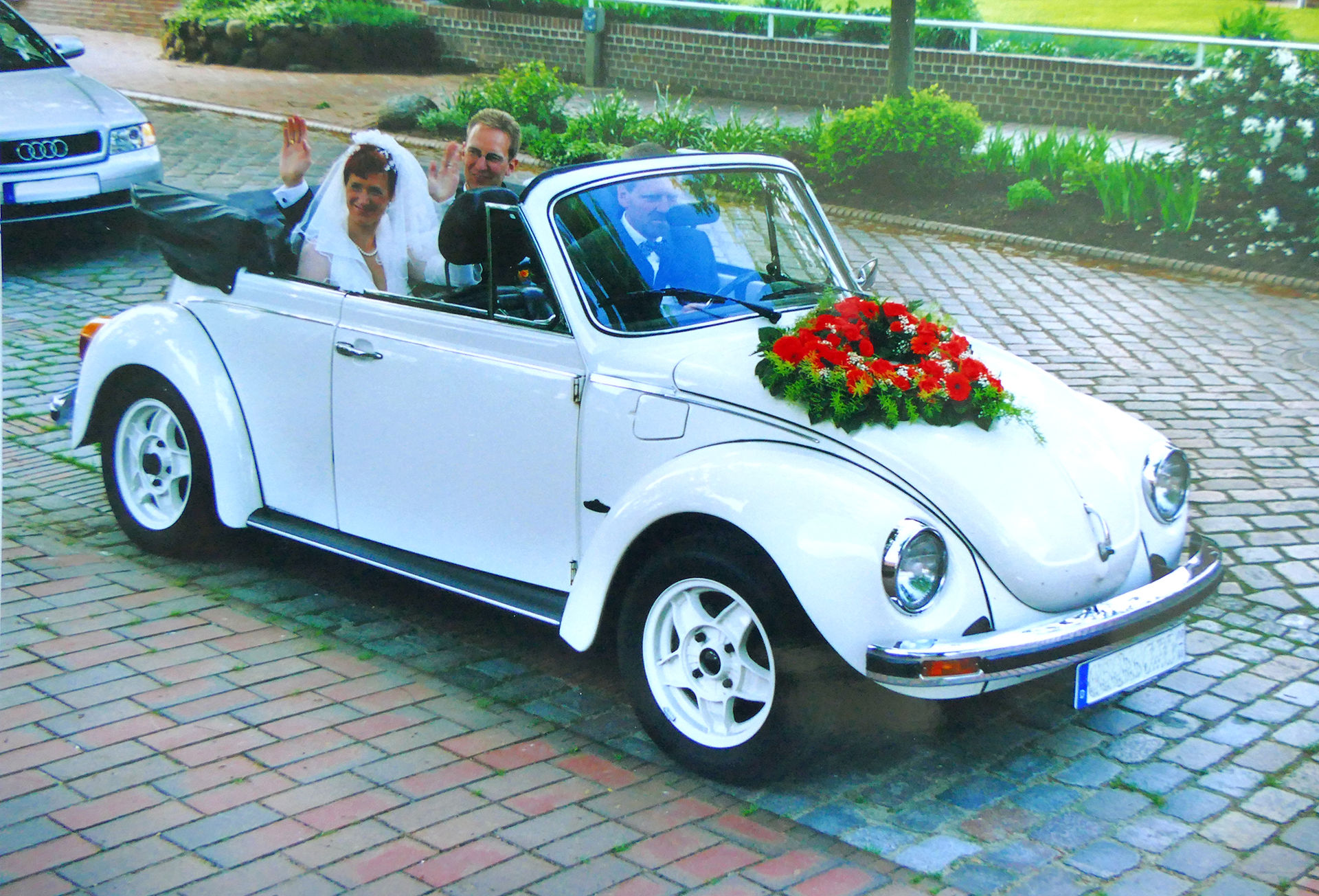Hochzeitspaar im weißen VW Käfer Cabrio