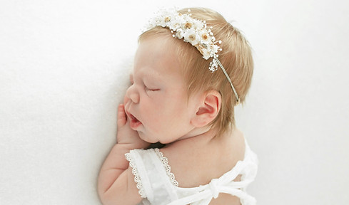 baby wearing white and flowers in her hair