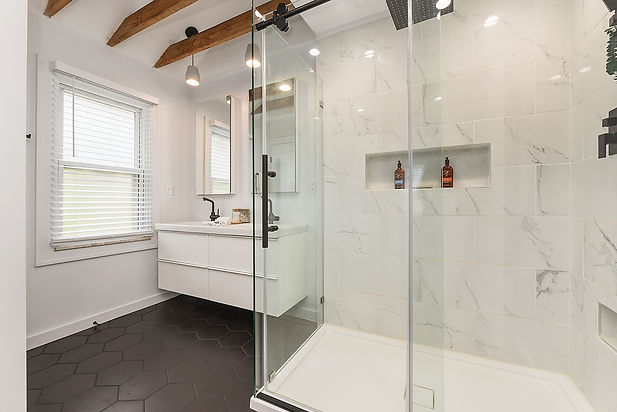 A renovated bathroom with tile floors and tile shower surround