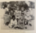 Black and white photo of the author with six pupils sitting on a bench next to her.
