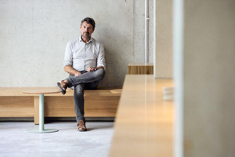 Unternehmer sitzt entspannt auf Bank. Indoor Businessportrait Volker Meyer-Lücke Care4Coffee Gmbh