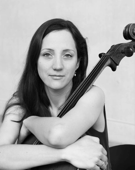 Musiker Porträt in Schwarz weiß. Frau mit dunklem Haar hat ihre Arme um ein Cello und schaut entspannt in die Kamera.