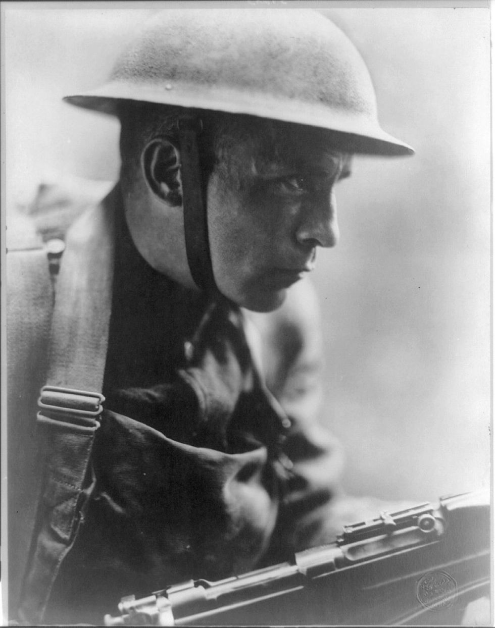 Close-up photograph of an American World War I soldier, called a "doughboy," in full combat dress. The photograph is entitled, "Over the Top."