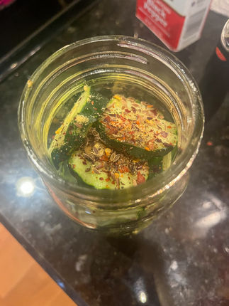 cucumber chips with mustard seed, pepper, and red pepper flakes in open mason jar