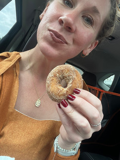 Woman smiles as she is about to eat a cider donut