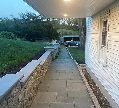Outdoor recessed lighting within the roof of a home illuminating stone pathway.