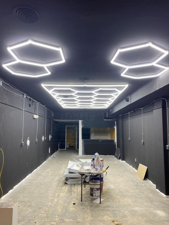 Abstract hexagon lighting design within an all black room.