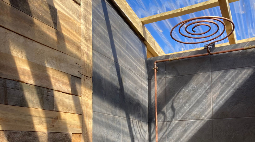 A handmade curved copper shower with reclaimed wood panelled walls.