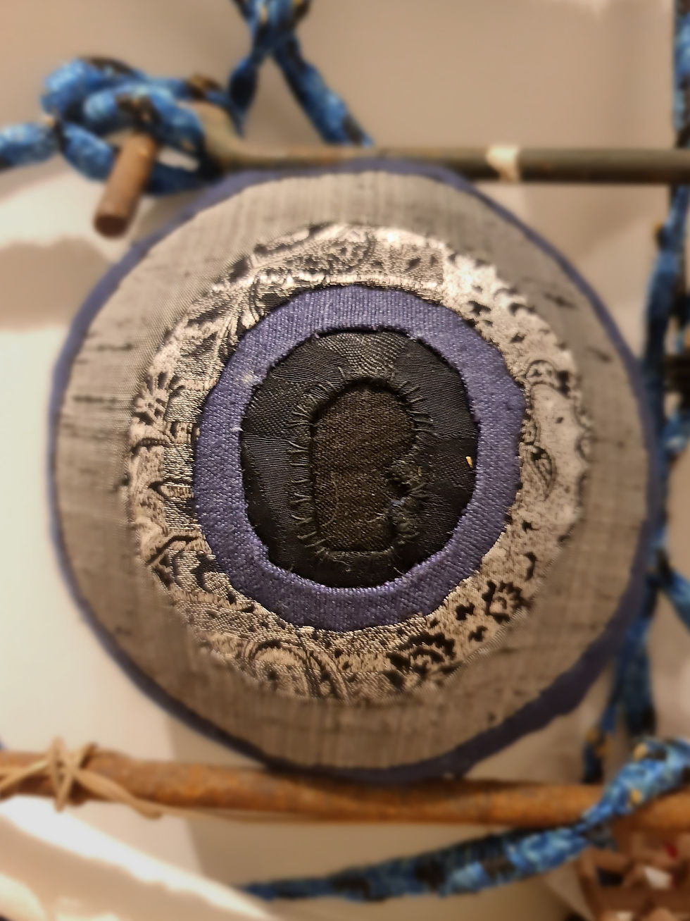 A soft, round textile form with layered openings. What began as a keyhole now resembles an eyeball or even an iris scanner; the shape shifts depending on how we name it. Mixed media, 2025.