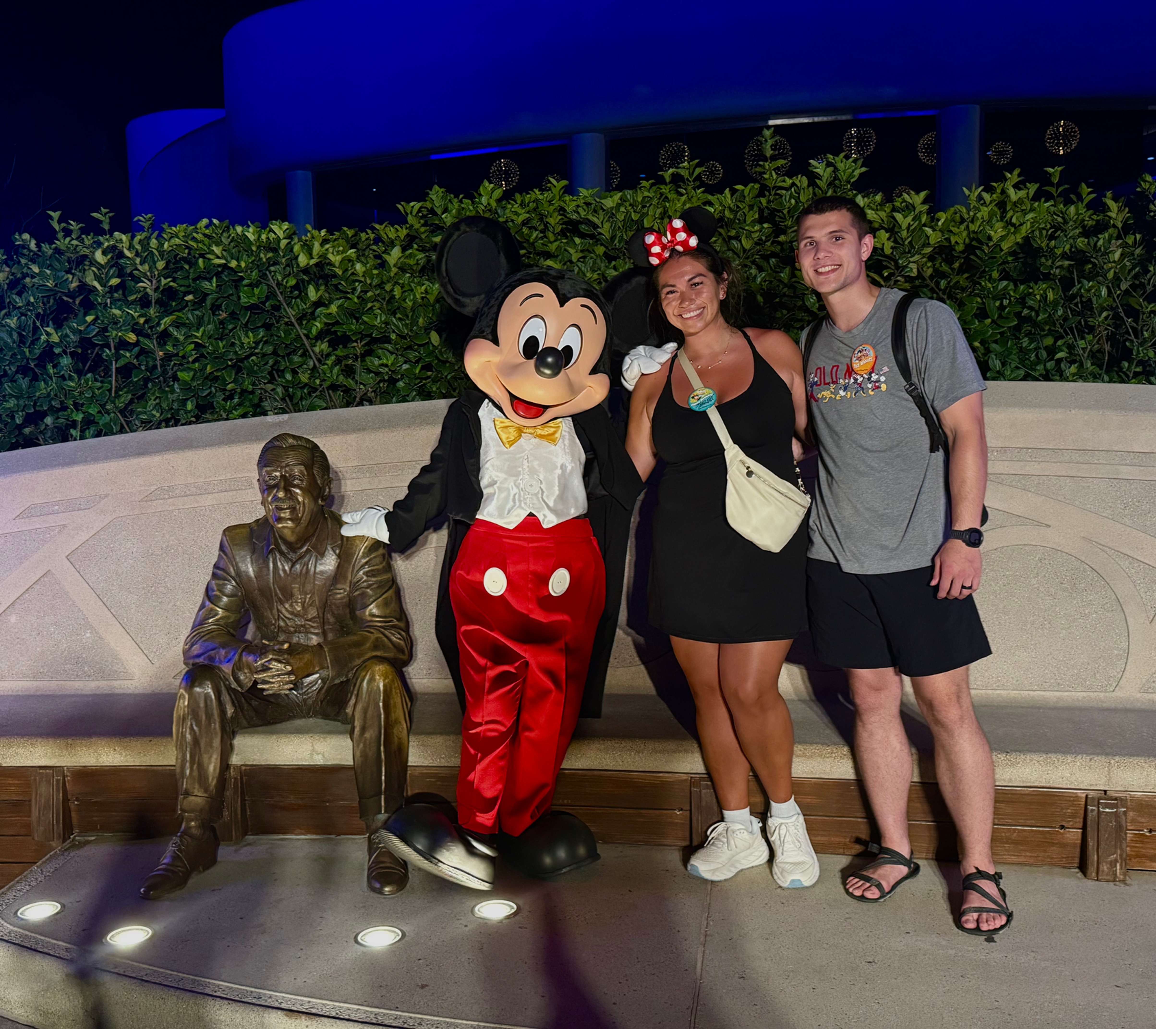 Good Trip Advisor Shalah at Disney after hours standing with Mickey Mouse next to a statue of Walt Disney